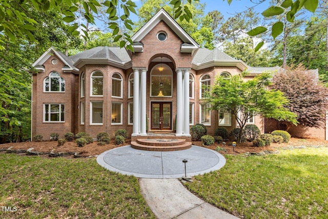 view of front of house featuring a front yard, french doors, and brick siding