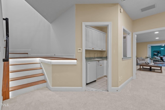 corridor featuring visible vents, light carpet, stairs, and a sink