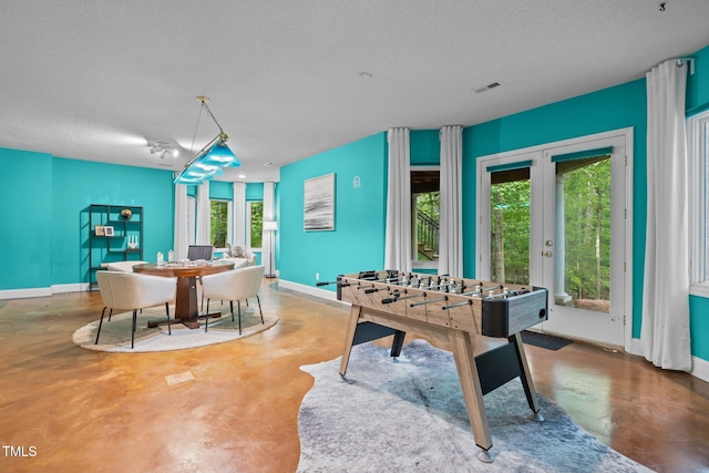recreation room with baseboards, concrete flooring, a textured ceiling, and french doors