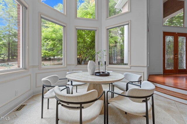 sunroom / solarium featuring a wealth of natural light, french doors, and a decorative wall