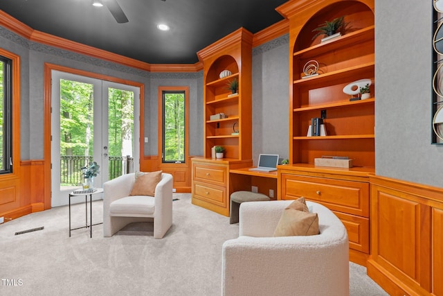sitting room with visible vents, a wainscoted wall, ornamental molding, light carpet, and a ceiling fan