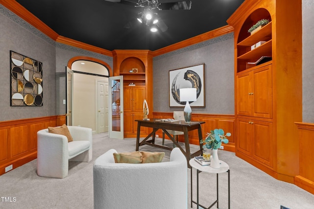 home office featuring built in shelves, crown molding, wainscoting, and light carpet