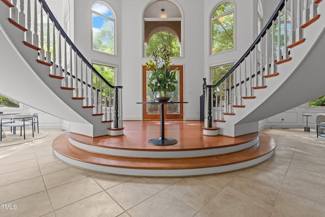 foyer featuring tile patterned floors, a wealth of natural light, stairs, and a towering ceiling