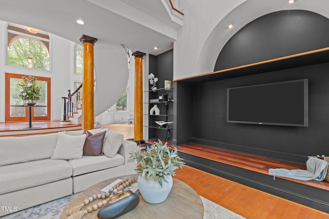 living room with recessed lighting, stairway, ornate columns, a towering ceiling, and wood finished floors