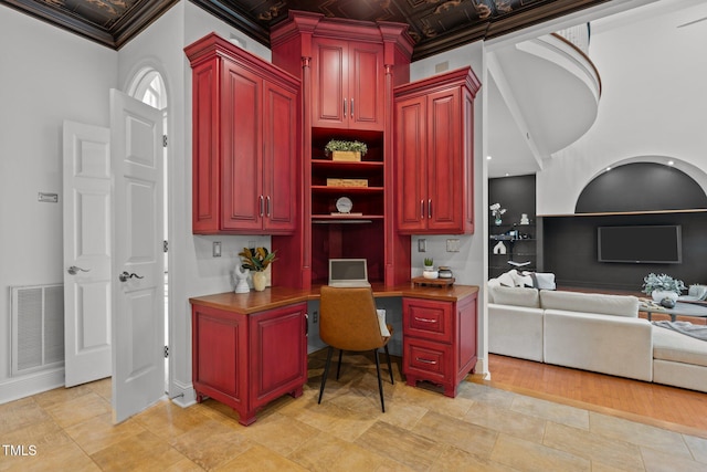 home office featuring built in desk, crown molding, visible vents, and baseboards