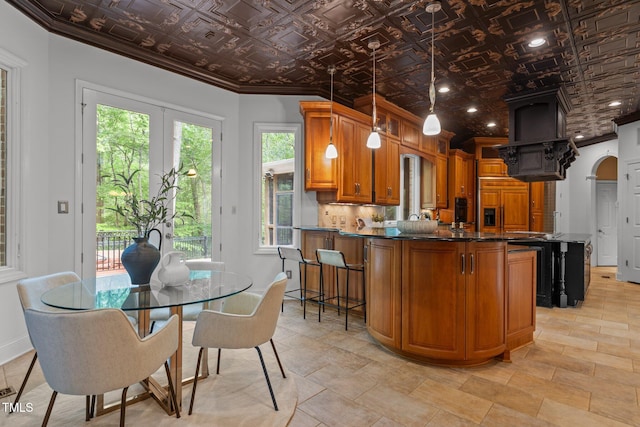 kitchen with a breakfast bar area, brown cabinets, ornamental molding, an ornate ceiling, and a peninsula