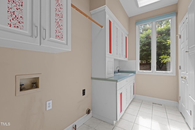 clothes washing area with cabinet space, washer hookup, a sink, baseboards, and visible vents