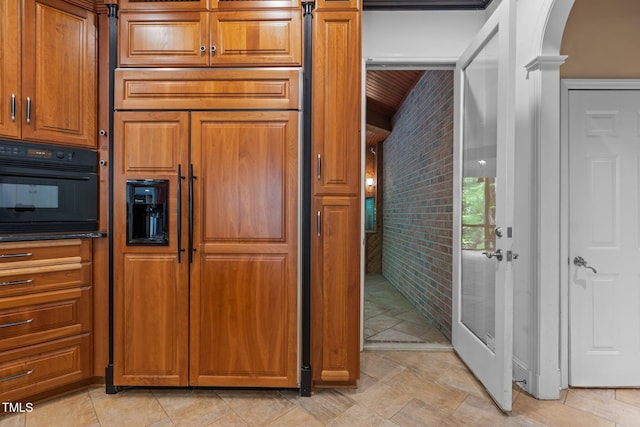 kitchen featuring brown cabinets, paneled built in fridge, arched walkways, oven, and brick wall