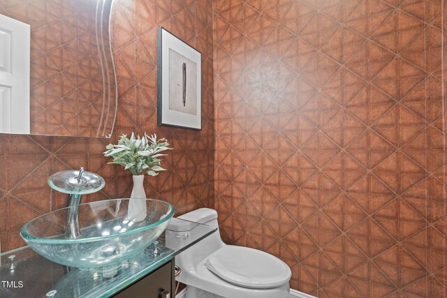 half bathroom with vanity, toilet, and tile walls