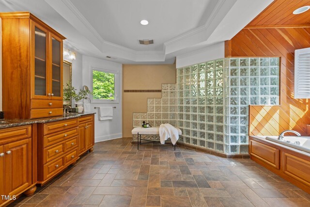 bathroom featuring a tray ceiling, visible vents, wood walls, baseboards, and a garden tub