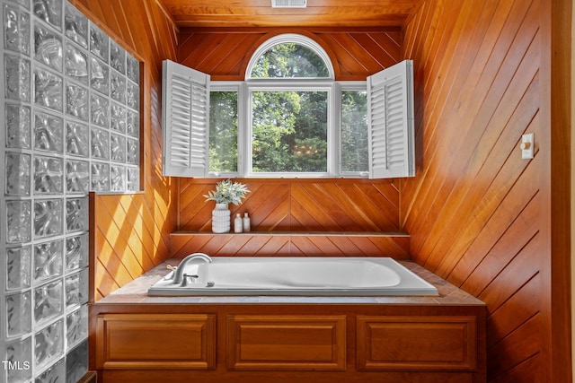 bathroom with visible vents, wooden walls, and a garden tub