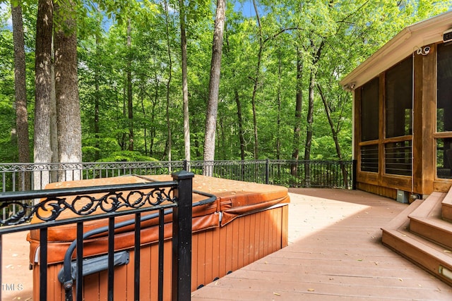 wooden deck with a sunroom and a hot tub