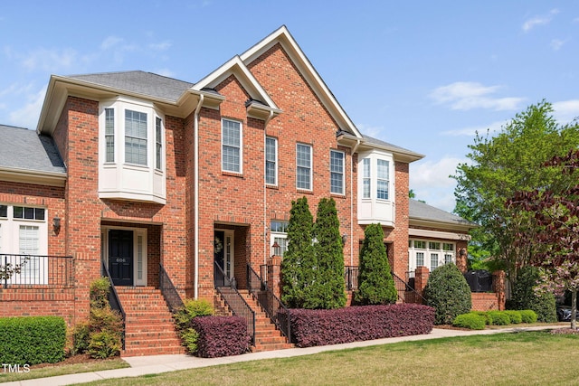 view of front facade with roof with shingles and brick siding