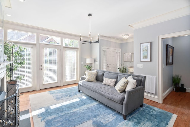 living room featuring visible vents, baseboards, a notable chandelier, crown molding, and wood finished floors