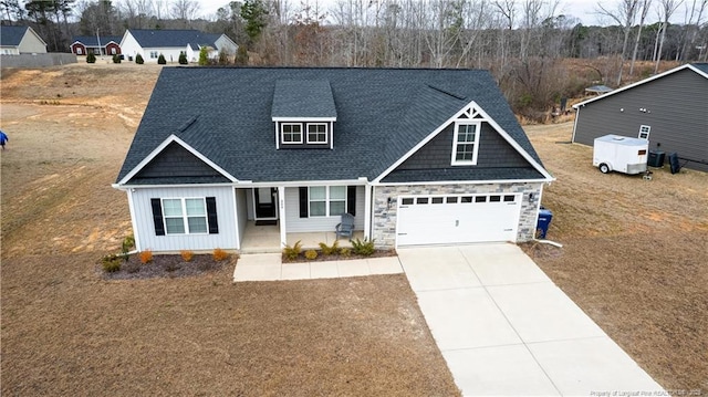 craftsman inspired home featuring board and batten siding, a porch, stone siding, a shingled roof, and concrete driveway