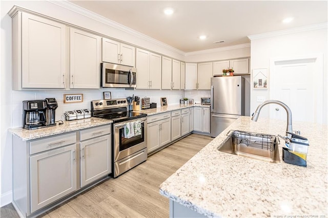 kitchen featuring ornamental molding, light wood-style flooring, gray cabinetry, appliances with stainless steel finishes, and a sink