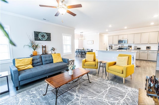 living room featuring ornamental molding, light wood-style flooring, recessed lighting, and ceiling fan with notable chandelier