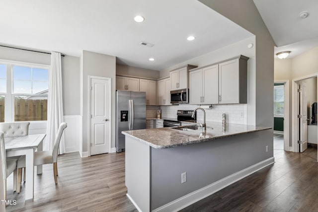 1209 Big Field Dr, Castle Hayne, NC 28429 - kitchen featuring light stone countertops, a peninsula, appliances with stainless steel finishes, wood finished floors, and a sink