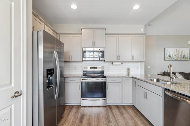1209 Big Field Dr, Castle Hayne, NC 28429 - kitchen featuring tasteful backsplash, a sink, light wood-style floors, light stone countertops, and stainless steel appliances