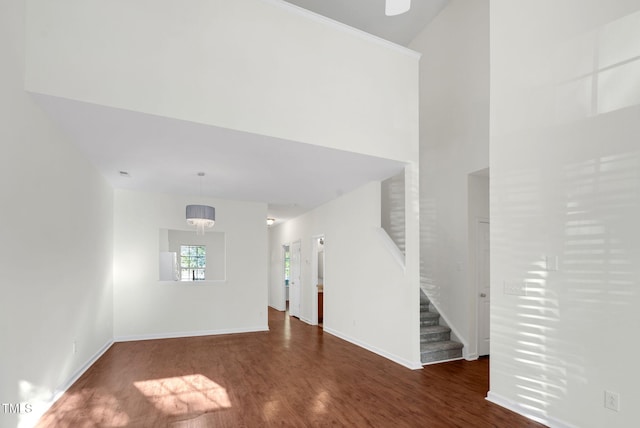 unfurnished living room with baseboards, wood finished floors, and stairs