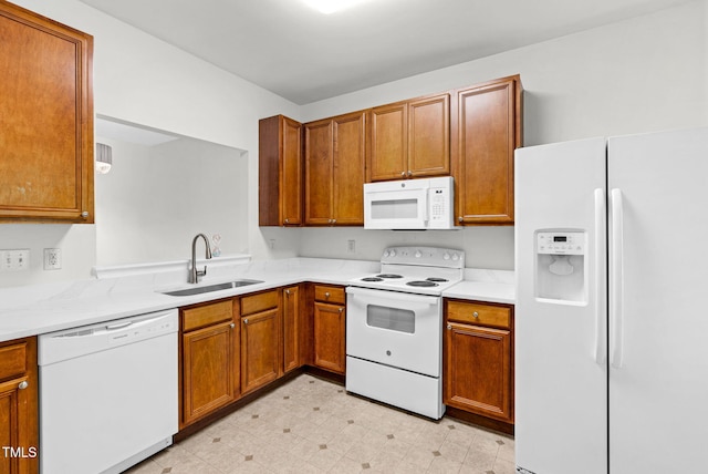 kitchen with a sink, brown cabinetry, light countertops, and white appliances