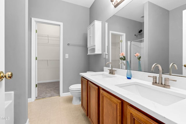 full bathroom with a sink, a walk in closet, double vanity, and a shower with shower door