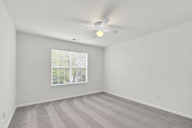 carpeted empty room featuring visible vents, a ceiling fan, and baseboards