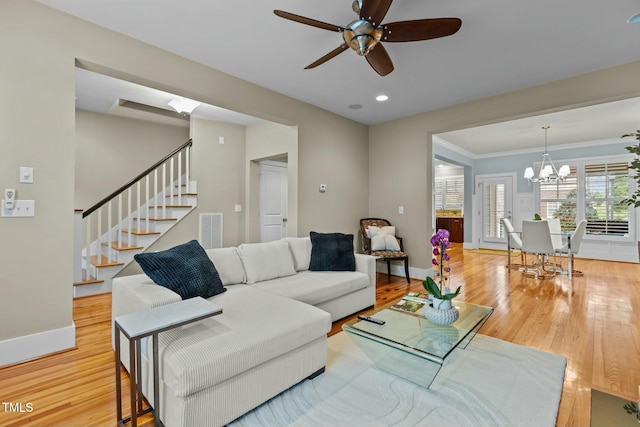 living room with baseboards, visible vents, ceiling fan with notable chandelier, stairs, and light wood-type flooring