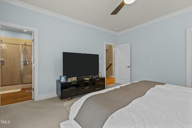 carpeted bedroom featuring ceiling fan, ensuite bath, baseboards, and ornamental molding