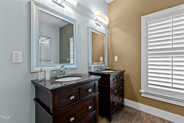 full bathroom featuring baseboards, two vanities, and a sink