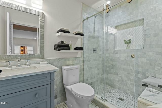 full bath featuring tile walls, toilet, vanity, a stall shower, and tile patterned flooring