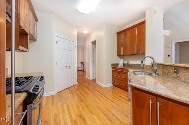 113 Beeley Ct, Cary, NC 27519 - kitchen with baseboards, a sink, light wood-style floors, brown cabinets, and light stone counters