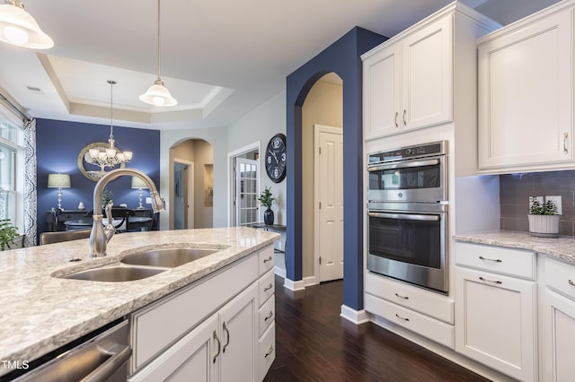 1005 Vesper Ct, Durham, NC 27703 - kitchen with arched walkways, a sink, appliances with stainless steel finishes, dark wood-type flooring, and a raised ceiling