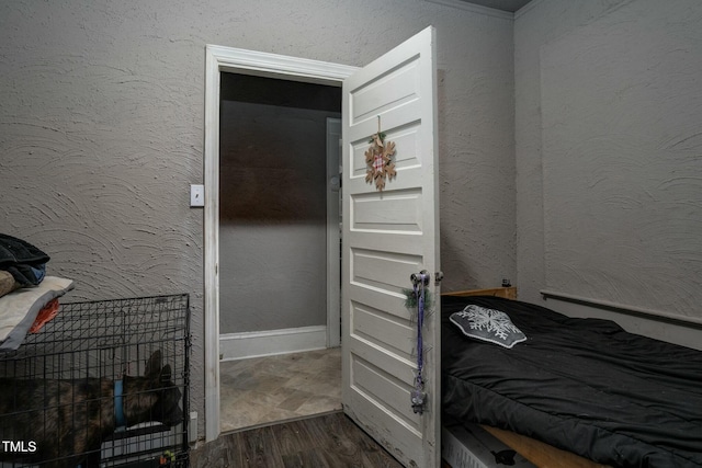 bedroom with a textured wall and dark wood-style floors