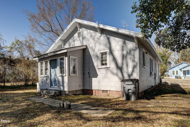 rear view of property featuring crawl space, entry steps, and a lawn