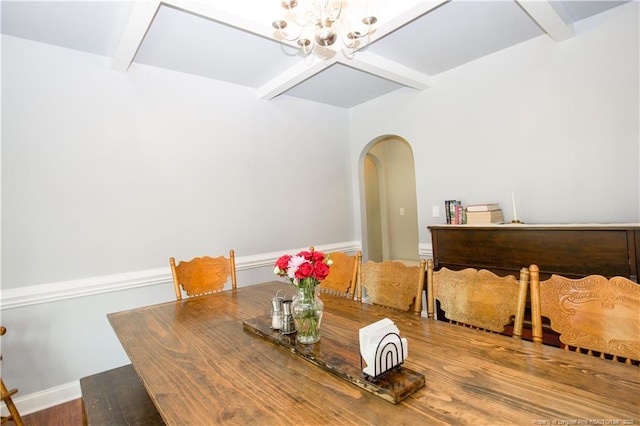 dining space featuring arched walkways, beamed ceiling, a notable chandelier, and baseboards