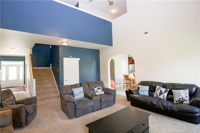 carpeted living area featuring stairway, french doors, a ceiling fan, visible vents, and arched walkways