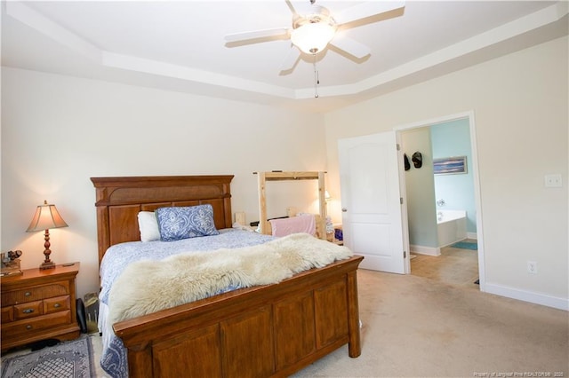 bedroom with baseboards, a ceiling fan, connected bathroom, a tray ceiling, and light colored carpet
