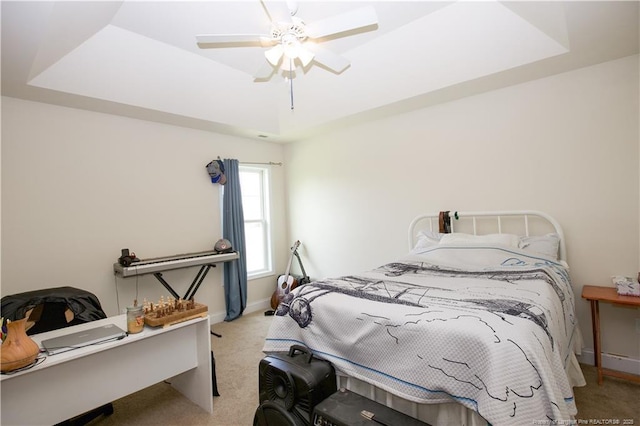 bedroom featuring ceiling fan, a tray ceiling, baseboards, and carpet floors