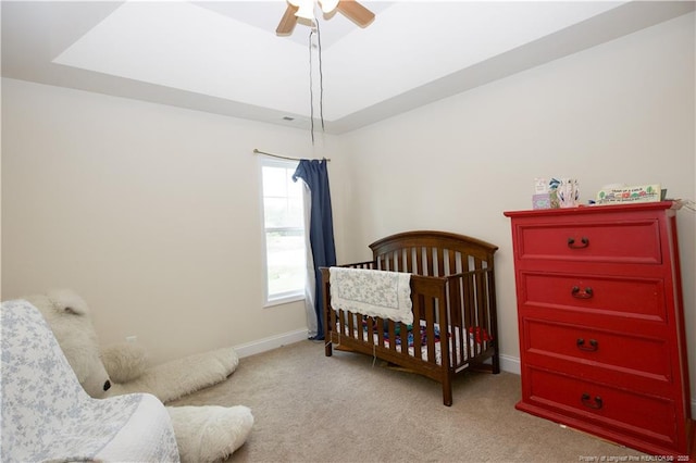 bedroom with carpet floors, baseboards, a raised ceiling, and a ceiling fan