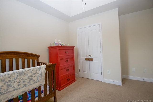 bedroom with a closet, baseboards, and light colored carpet