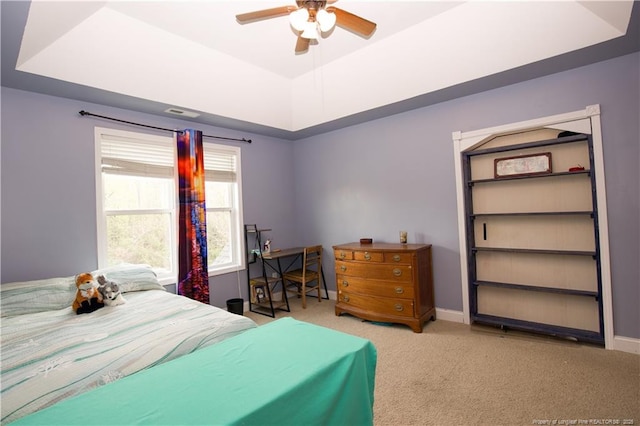 bedroom with a tray ceiling, baseboards, and carpet floors