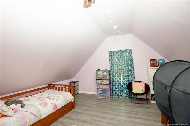 bedroom featuring lofted ceiling, visible vents, baseboards, and wood finished floors