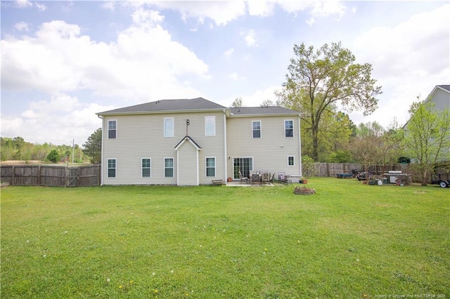 rear view of property featuring a yard, a fenced backyard, a fire pit, and a patio area