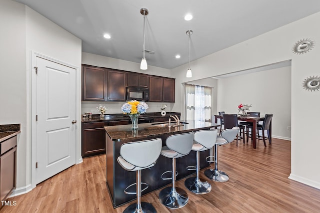 95 Shady Creek Trl, Garner, NC 27529 - kitchen featuring a sink, a kitchen bar, black microwave, light wood-style flooring, and dark brown cabinets