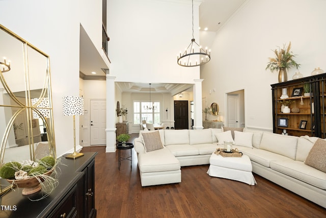 living room with crown molding, ornate columns, a chandelier, and dark wood-style floors