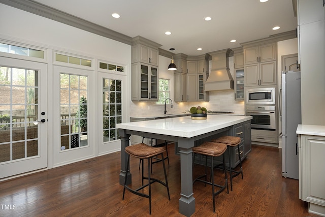 kitchen with gray cabinets, a center island, custom range hood, and stainless steel appliances