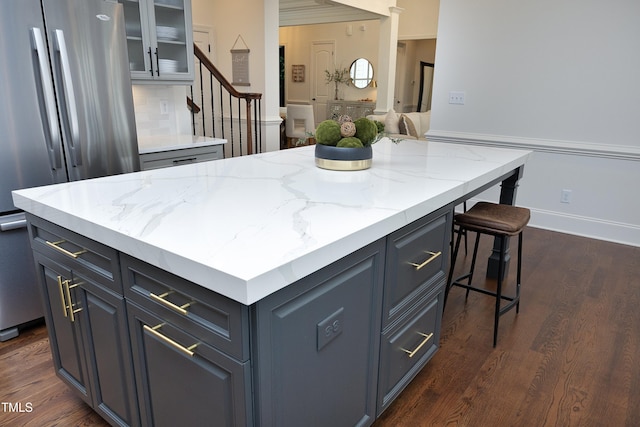 kitchen featuring glass insert cabinets, a kitchen breakfast bar, freestanding refrigerator, and dark wood finished floors