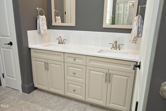 full bath with a sink, tasteful backsplash, double vanity, and a shower with door