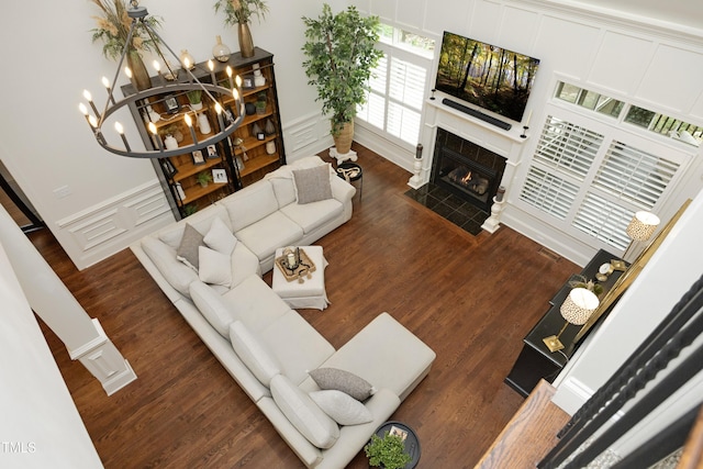 living room featuring a decorative wall, a tiled fireplace, a chandelier, and wood finished floors